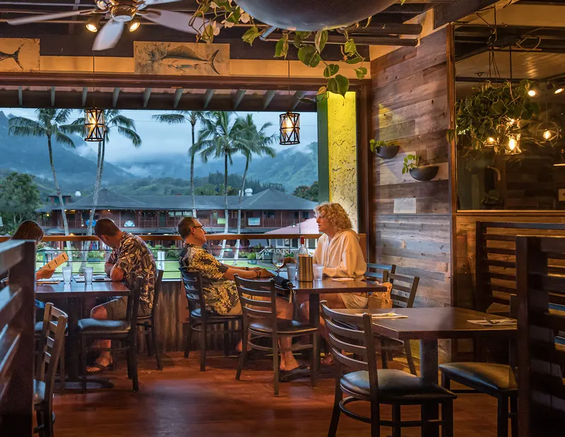 Guests dining by the open-air windows at dusk